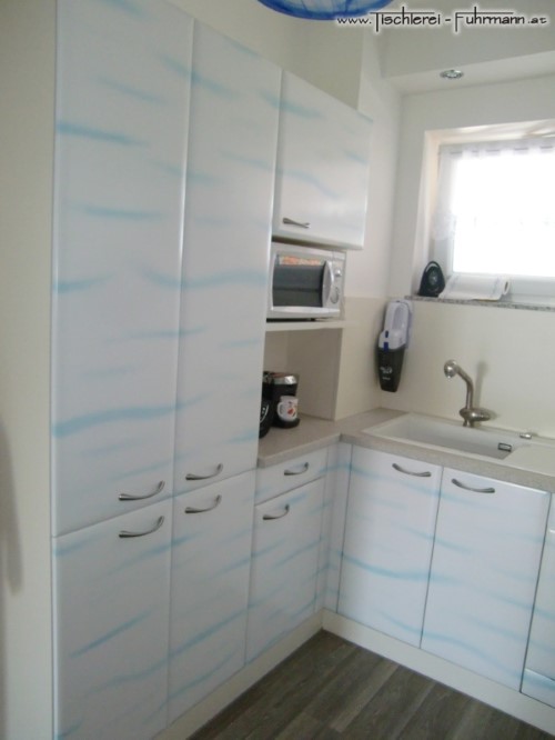 Blaues Wolkenmuster auf weiß lackierten Küchenfronten